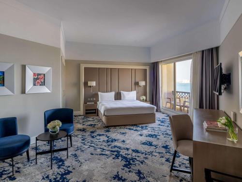 a hotel room with a bed and a desk and chairs at Rixos Bab Al Bahr - Ultra All Inclusive in Ras al Khaimah