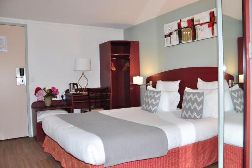 a bedroom with a large bed and a desk at Hôtel des Arcades de Cachan - Grand Paris Sud in Cachan