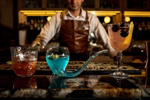 a man standing behind a bar with two cocktails at Rixos Premium Dubrovnik in Dubrovnik