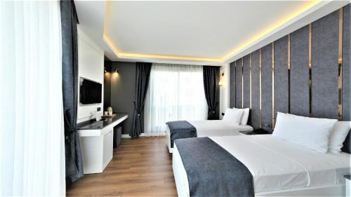 a hotel room with two beds and a television at Mai İnci Otel in Antalya