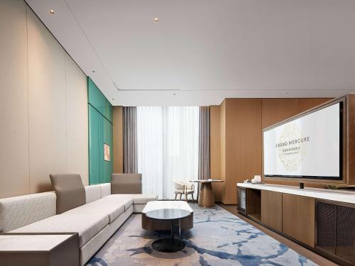 a living room with a couch and a flat screen tv at Grand Mercure Chengdu East in Chengdu