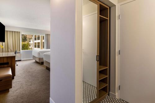 a hotel room with a closet and a bedroom at Sonesta Select San Francisco Airport Oyster Point Waterfront in South San Francisco