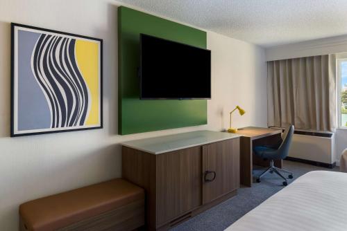 a hotel room with a desk and a tv on the wall at Sonesta Select San Francisco Airport Oyster Point Waterfront in South San Francisco