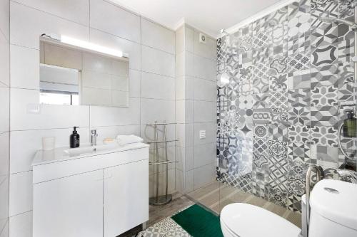 a white bathroom with a toilet and a shower at Praia da Rocha Mar Guest House in Portimão