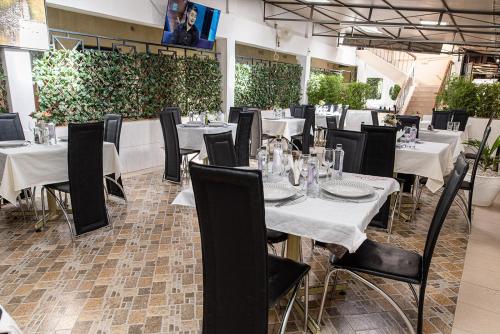 a dining room with white tables and black chairs at The Stand Leisure Hotel in Nairobi