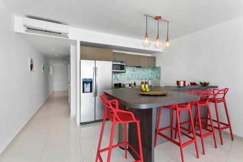 a kitchen with a black island with red stools at Vue époustouflante sur le lagon pour 4p in Baie Nettle