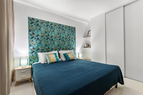 een slaapkamer met een groot bed en een blauwe deken bij Vue époustouflante sur le lagon pour 4p in Saint Martin