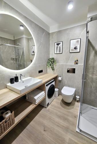 y baño con lavabo, aseo y ducha. en Pine Point Apartament with shared Pools, Jacuzzi, Sauna & Gym, en Szklarska Poręba