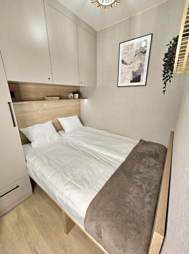 1 dormitorio pequeño con 1 cama con sábanas blancas en Pine Point Apartament with shared Pools, Jacuzzi, Sauna & Gym, en Szklarska Poręba