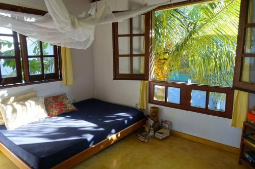 a bedroom with a bed in a room with windows at Beautiful upstairs apartment - Top view in Itacaré