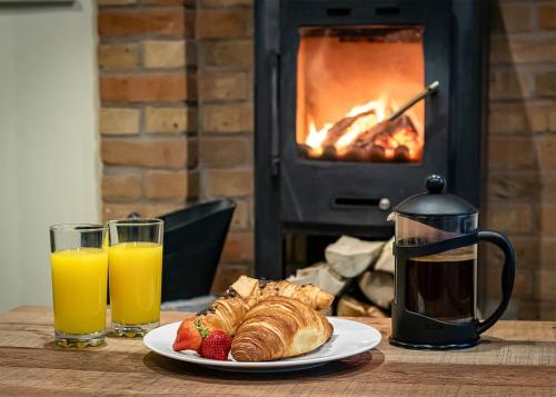 a plate of croissants and strawberries on a table with a fireplace at Ramshorn Estate Woodland Lodges in Oakamoor