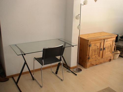 a glass desk with a chair and a lamp at Relax aux Paccots : été comme hiver in Les Paccots