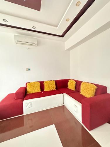 a red couch in a white room with yellow pillows at Airport Lux Rooms in Kiembi Samaki