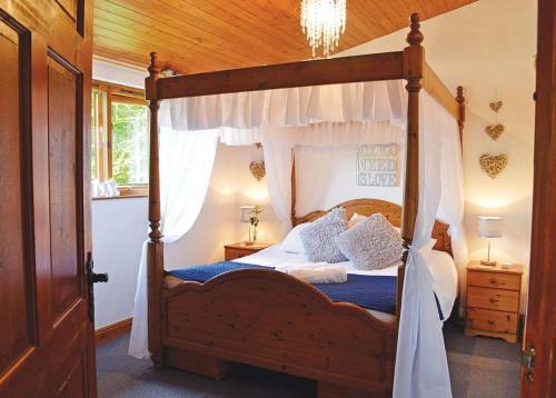 a bedroom with a canopy bed with blue sheets and pillows at Brookside Leisure Park in Chirk
