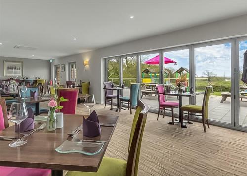 a restaurant with tables and chairs and windows at Croft Country Park in Reynalton