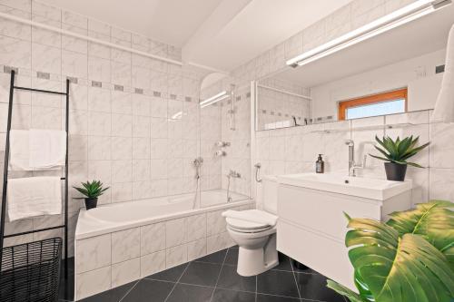 y baño blanco con aseo, bañera y lavamanos. en FeWo Bodensee - See- und Bergsicht, en Friedrichshafen