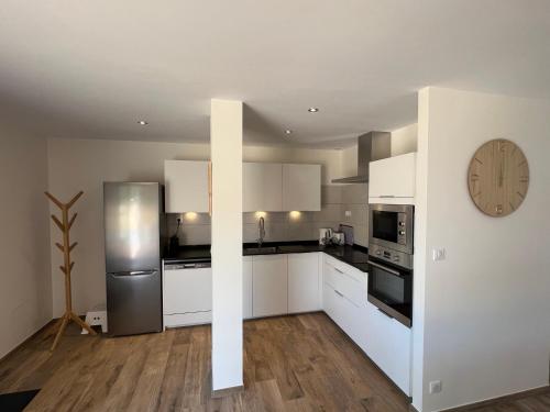 une cuisine avec des placards blancs et une horloge murale dans l'établissement Maison cosy à Lacanau, à Lacanau