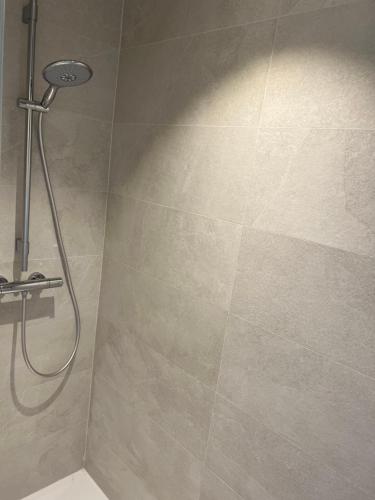 une douche dans une salle de bain avec un mur carrelé dans l'établissement Maison cosy à Lacanau, à Lacanau