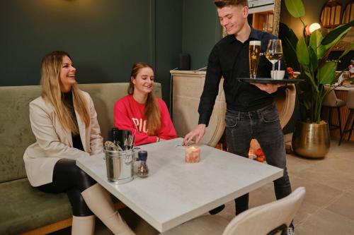 a man presenting a table with a man holding a tray at Hotel Halbert in Groningen