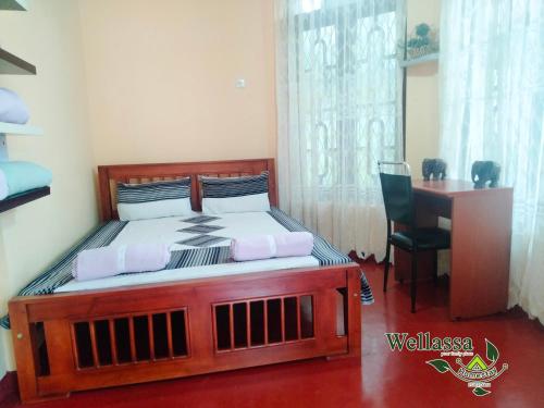 a bedroom with a wooden bed with a desk and a window at wellassa homestay in Badulla