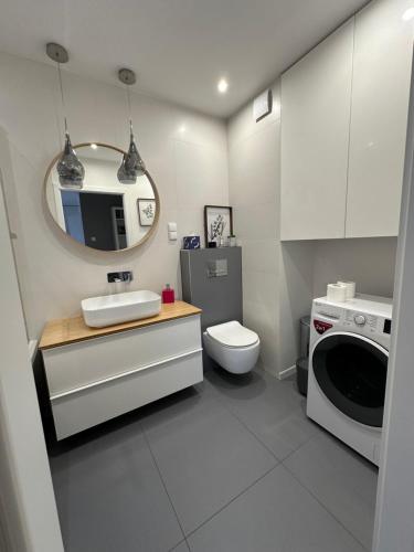 a bathroom with a sink and a toilet and a mirror at Apartament Szczytno Zielona in Szczytno