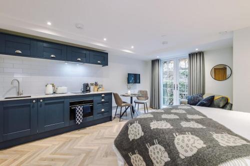 a kitchen and living room with a bed and a kitchen and a counter at Deluxe Studio Apartment with Private Balcony in Stoney Middleton