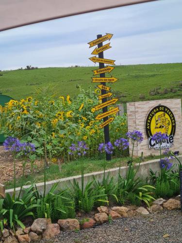 a directional sign in a garden with flowers at Refúgio dos Coiotes in Cambara do Sul