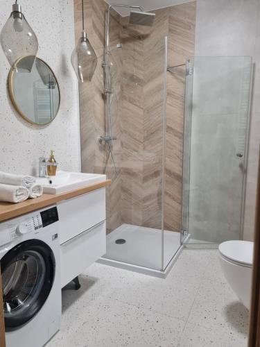 a bathroom with a shower and a washing machine at Airport Apartment in Warsaw