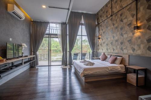 a bedroom with a bed and a large window at Kwai Tara Riverside Villas in Sai Yok