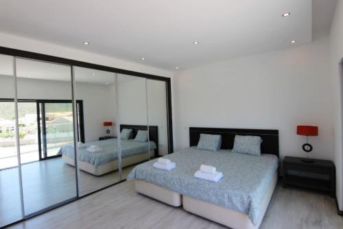a bedroom with two beds and glass walls at Villa Goncinha - Piscina in Loulé