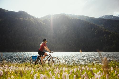 a woman riding a bike in front of a lake at Hotel Alpenrose in San Valentino alla Muta