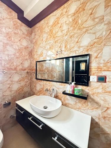 ein Bad mit einem Waschbecken und einem Spiegel in der Unterkunft Airport Lux Rooms in Kiembi Samaki