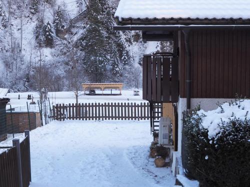 a snow covered yard with a bench and a fence at Ciasa de Lucky in Moena