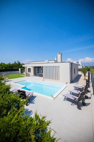 a swimming pool with lounge chairs next to a building at Villa Rose Nin ZadarVillas in Nin