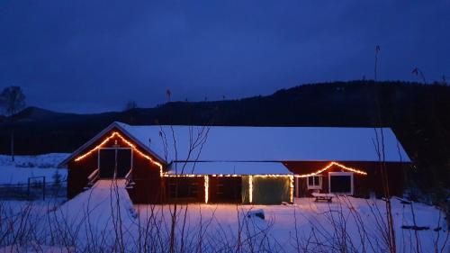 a barn covered in lights in the snow at night at Vikinggård Cottages in Höljes