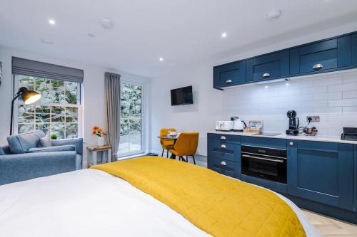 a bedroom with a bed and a kitchen with blue cabinets at No.6 - Studio Apartment with Private Terrace in Stony Middleton