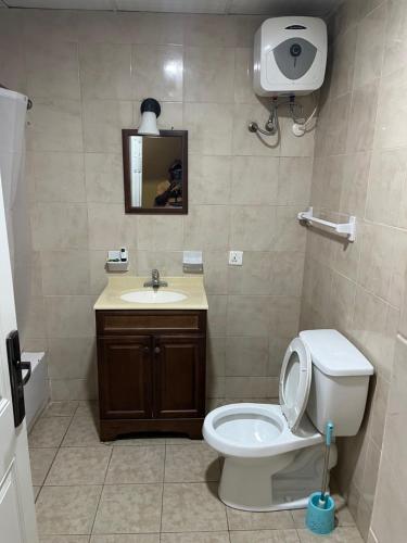 a bathroom with a toilet and a sink and a mirror at Enclave Hotel Abuja in Kagini