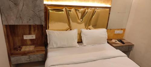 a bed with white pillows and a mirror in a room at THE UNITED HOTEL in Mumbai