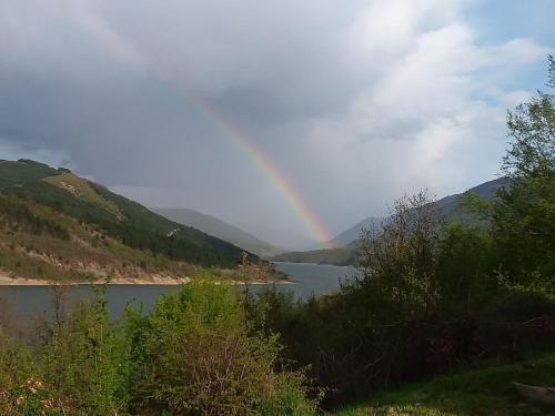 a rainbow over a lake with mountains in the background at Zavojsko jezero - Vila Jezero in Pirot