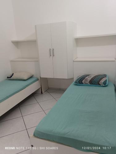 a small room with two beds and white cabinets at Pousada Brisamar Morro dos Conventos in Conventos