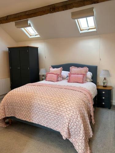 a bedroom with a large bed with pink pillows at The Old House Barn in Staverton