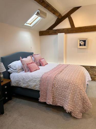 a bedroom with a large bed with pink pillows at The Old House Barn in Staverton