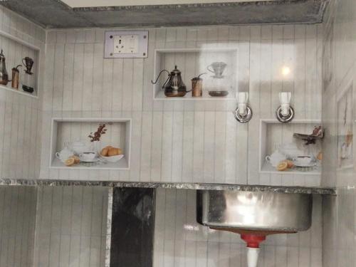 a kitchen with a sink and shelves on the wall at राम जानकी भवन होम स्टे in Faizābād