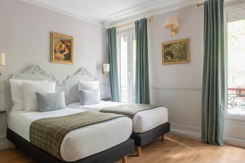 パリにあるホテル ドゥ ラ ポルト ドレーのベッド2台と窓が備わるホテルルームです。