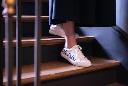 a woman in white shoes on the stairs at Hôtel De La Porte Dorée in Paris