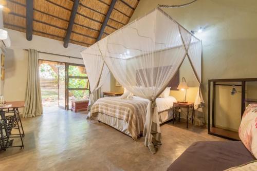 a bedroom with a bed with a mosquito net at Nguni Lodge in Victoria Falls