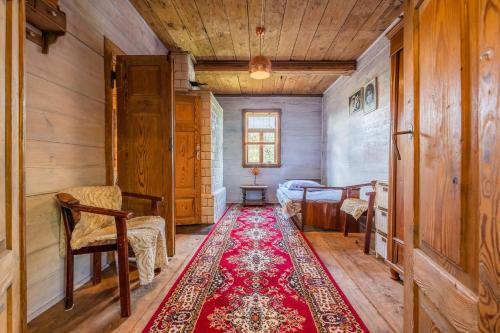 um quarto com um tapete vermelho num quarto com uma cama em prawdziwy wiejski domeczek em Hajnówka