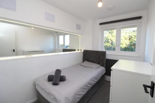 a small white room with a bed with a window at Modern Luxury Flat in London in Hither Green