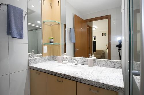 a bathroom with a sink and a large mirror at Hotel Premier Residence Brasília - Ozped Flats in Brasília