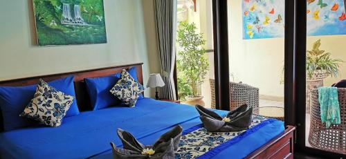a bedroom with a blue bed with black and white pillows at Villa Silence in Lovina